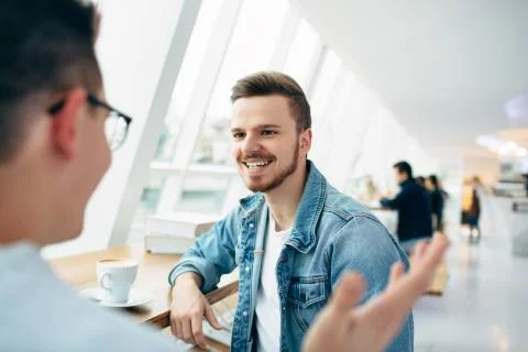 Men are sitting in front of the table near window Stock Photos