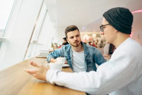 Men are sitting in front of the table near window Stock Photos