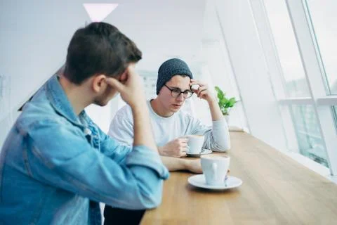 Men are sitting in front of the table near window Stock Photos