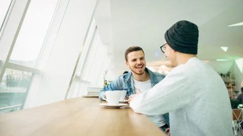 Men are sitting in front of the table near window Stock Photos