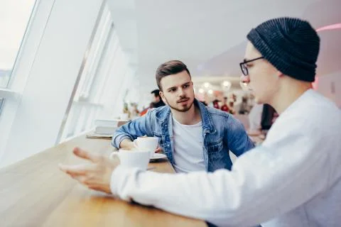 Men are sitting in front of the table near window Stock Photos
