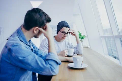Men are sitting in front of the table near window Stock Photos