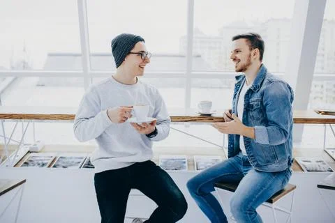 Men are sitting in front of the table near window Stock Photos