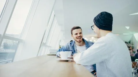 Men are sitting in front of the table near window Stock Photos