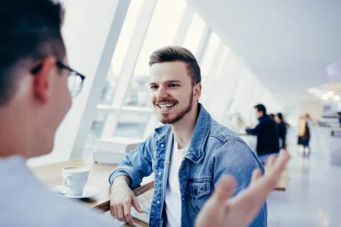 Men are sitting in front of the table near window Stock Photos