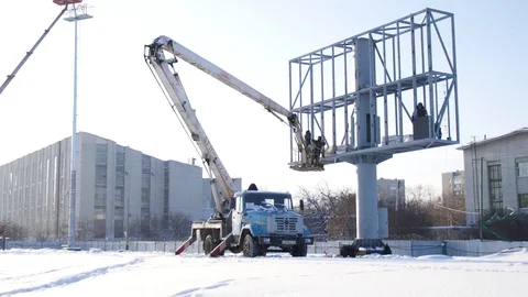 Men assemble Billboard on tap. Builder on a Lift Platform at a construction site Vídeos de archivo 84746085