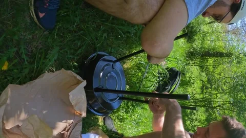Men assemble a mini grill for cooking steaks outdoors with care for the Stock Footage 310934685