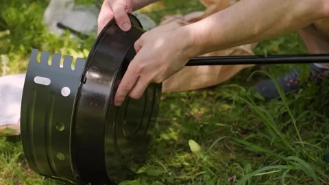 Men assemble a safe mini grill for cooking steaks without risking grass fires in Stock Footage 310934875