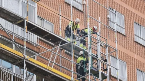 Men assemble a scaffold on a building facade Stock Footage 124940028