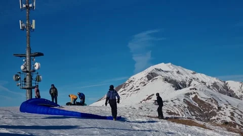 Men assist each other in preparing a blue paraglider for flight over the Swiss Stockbeeldmateriaal 327454459