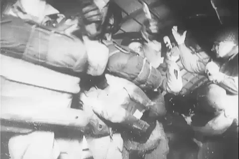 Men attach lines to overhead cables and bail out of aircraft - 1940 Video stock 103715840