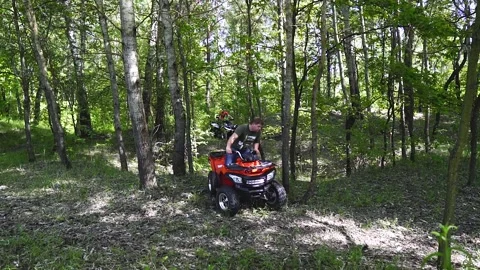 Men on an ATV drive through a hole in the forest and go in different directions. Stock Footage 139884479