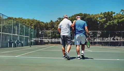 Men, back and walking with practice at tennis court for exercise, discussion and Fotos de archivo