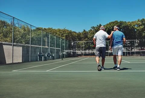 Men, back and walking with training at tennis court for exercise, discussion and Fotos de archivo