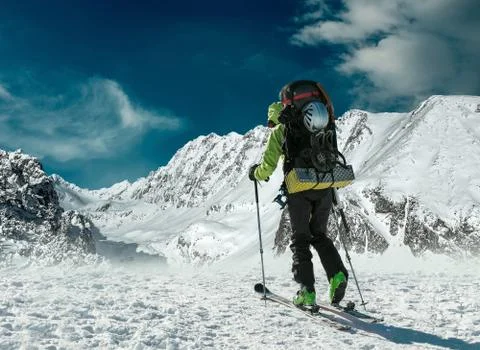 Men with backpack at ski goes to the top of mountain in sun day Stock Photos