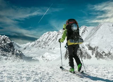 Men with backpack at ski goes to the top of mountain in sun day Stock Photos
