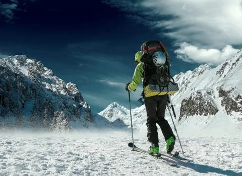 Men with backpack at ski goes to the top of mountain in sun day Stock Photos