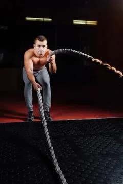 Men with battle rope in functional training fitness gym Stock Photos