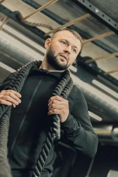 Men with battle rope in functional training fitness gym. Healthy lifestyle co Stock Photos