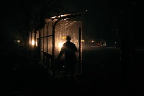 Men on the buss stop in full dark in the headlights. Streets without street Stock Photos