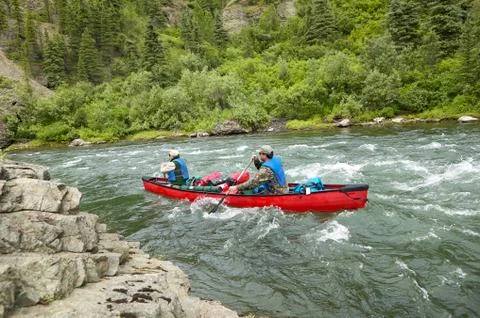 Men canoeing on rough river rapids in wild Alaska Stock Photos