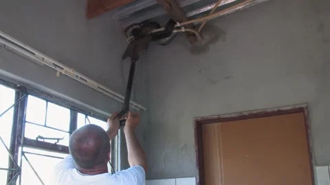 Men carefully handle a massive African rock python From house Indoor Ceilin.. Stockbeeldmateriaal 333721700