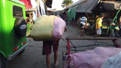 Men carrying heavy loads while walking on the street with building and and Vídeos de archivo 124080695