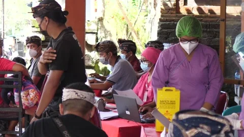 Men changing each other in queue for mandatory vaccine against covid-19. Bali Video stock 150947071