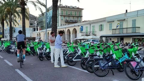 Men checking phones by a large electric bike rental in Nice Video stock 336923059