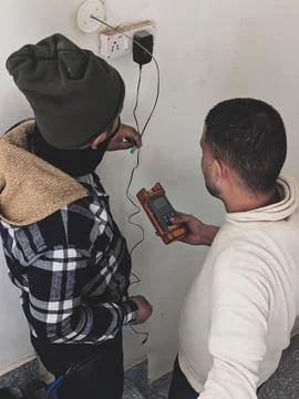 Men checking wall wiring with a multimeter Stock Photos
