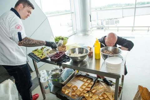 Men in chef uniforms serving snacks on table for degustation in Lviv airport  Stock Photos