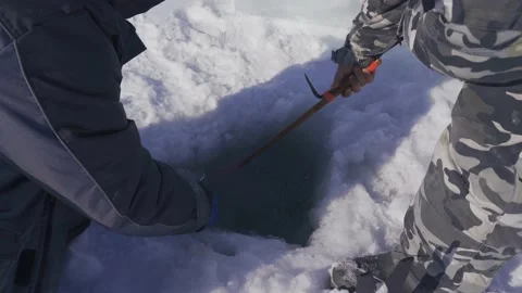Men clear the ice hole to catch fish and crabs. Stock Footage 149381790