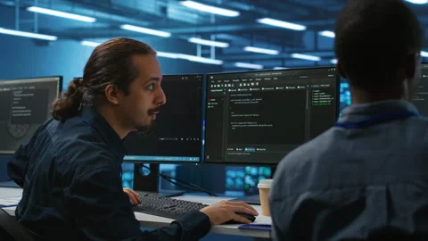 Men coding together in high tech server hub, using computers to analyze data, Video stock 276140155