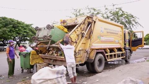 Men collaborates to loading trash from plastic recycle container to the trash tr Stock Footage 248091566