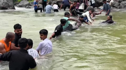 Men collaborating to cross a dangerous river forming a human safety chain 動画素材 340251841