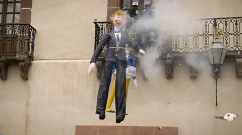 Men dangle a paper mache effigy of Donald Trump as it blows up with fireworks Stock Footage 61830146