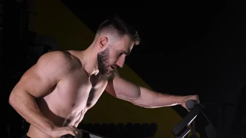 A men on a dark background in the gym doing cycling in the gym. Video stock 264765797