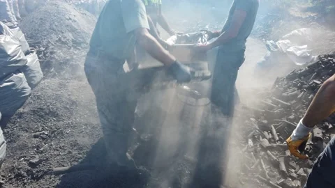 Men in dirty clothes sifting through burnt logs firewood packing coal into sacks Stock Footage 142513887