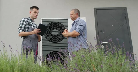 Men Discuss Heat Pump System Beside House Entrance Stock Footage 345621783