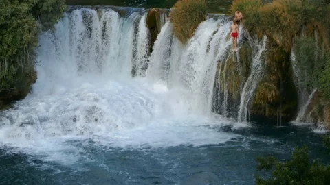 Men diving jumping in the water from the rock cliffs of a wild waterfall Stock Footage 90267939