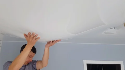 Men is drain water from a stretch ceiling filled with water through a tube. Stock Footage 128256817