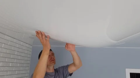 Men is drain water from a stretch ceiling filled with water through a tube. Stock Footage 128256821