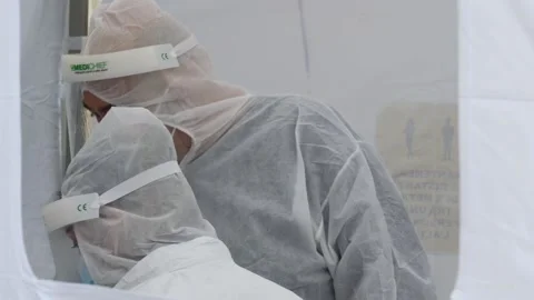 Men dressed in virus protection suite ready to make Covid test Stock Footage 143786053
