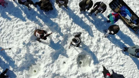 Men drill ice with an auger drill - ice fishing on a frozen river in winter. Stock Footage 179525733