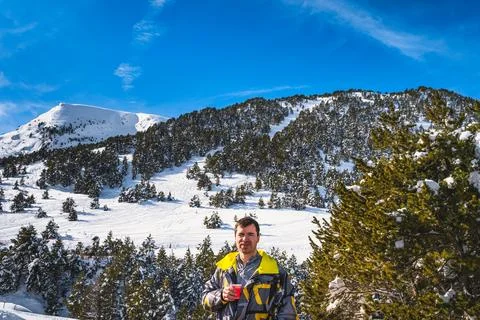 Men drinking coffee or tee with snowy forest and mountains in background, A.. Stock Photos