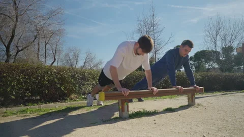 Men Engaging in Physical Activity Outside Completing PushUp Workout on Parallel Video stock 290033901