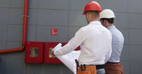 Men engineers discuss construction plan comparing with building Video stock 259291345