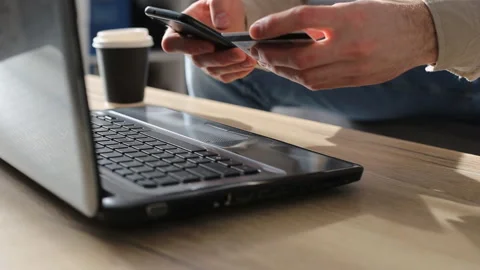 Mеn entering secure code on smartphone while shopping online using laptop with Stock Footage 127111704