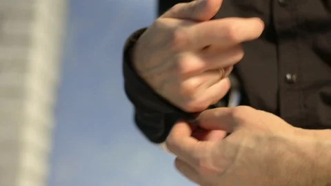 Men fasten a button on a sleeve of a dark brown shirt. Stock Footage 123363640