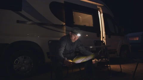 Men with Flashlight Reading Map Looking For Best Trails. Camping RV Park. Stock Footage 141038884